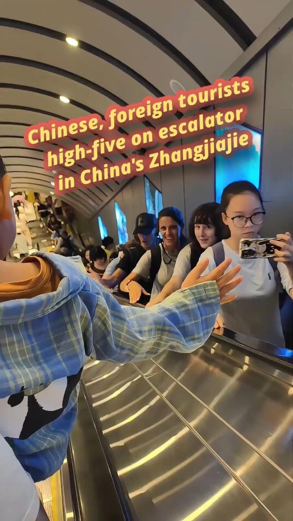 Chinese, foreign tourists high-five on escalator in China's Zhangjiajie